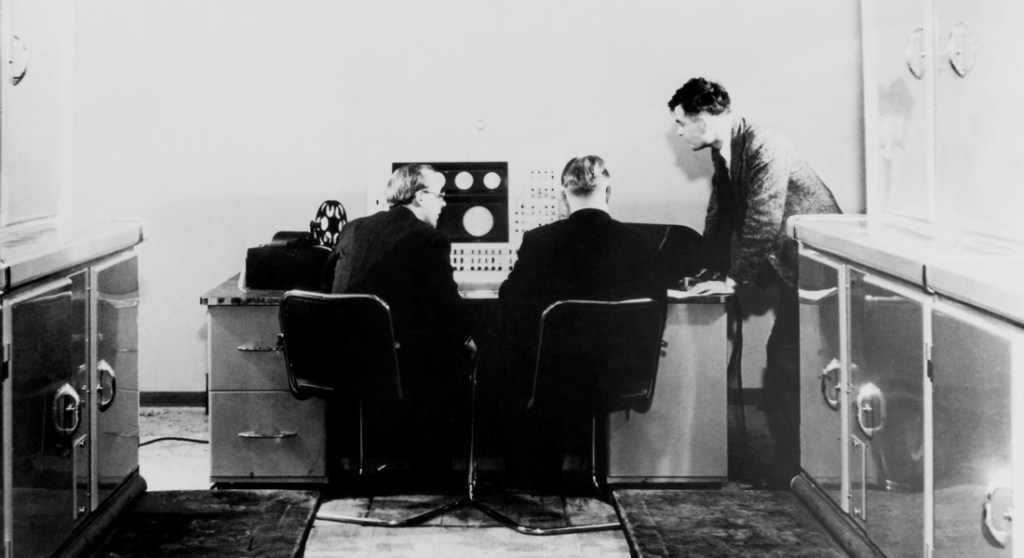 Alan Turing (standing) with colleagues working on the Manchester Mark 1 computer